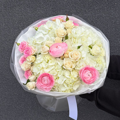 Bukiet z różowego ranunculusa, białej hortensji i róży gałązkowej